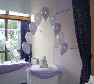 white and lilac balloon arch over cake table