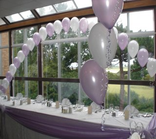 white and lilac balloon arch behind top table 